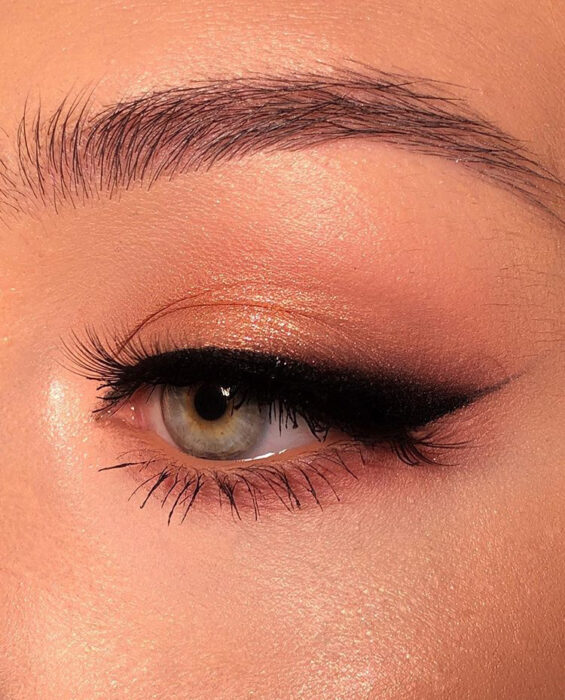 Chica con un maquillaje de ojos en color dorado con un cat eye negro grande