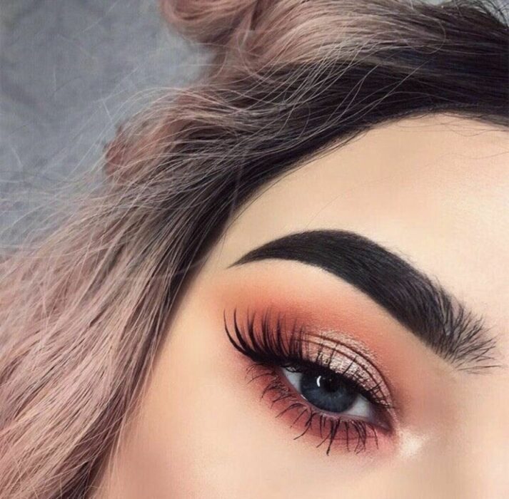 Chica con un maquillaje de ojos en colores cálidos de dorado y rosa