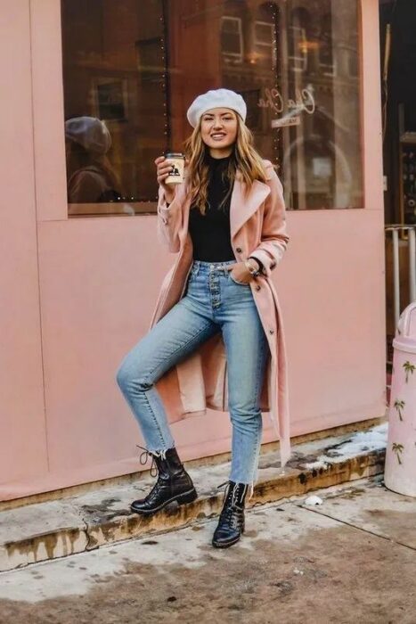 Outfit para la oficina de otoño-invierno de abrigo rosa palo, suéter negro, jeans, botines negros y boina gris
