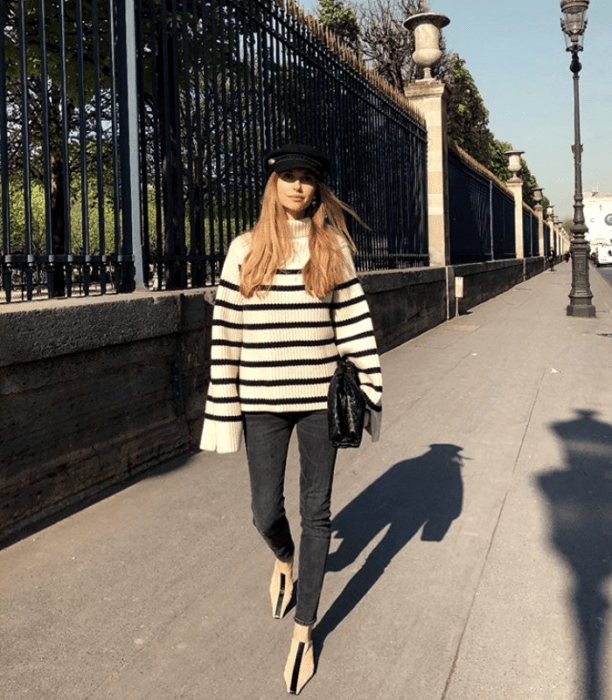 chica de cabello rubio usando un suéter de rayas blancas y negras, leggings y zapatillas con boina negra