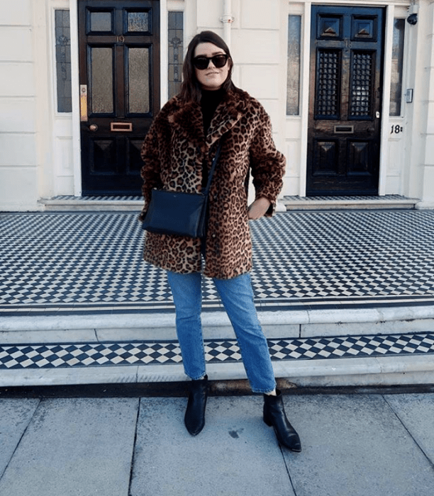 chica de cabello corto negro usando lentes de sol, abrigo de peluche de animal print, skinny jeans, y botines negros de cuero
