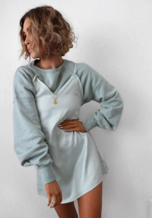 Looks con sudadera; chica de cabello corto bob, chino rubio durazno, con sudadera verde gris sobre un vestido de tirantes blanco