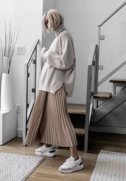 Looks con sudadera; mujer de cabello rubio platinado, hoodie blanco gris, con maxifalda tableada y tenis Skechers