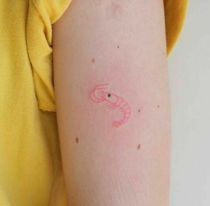 Chica con un tatuaje de color rosa en forma de camarón