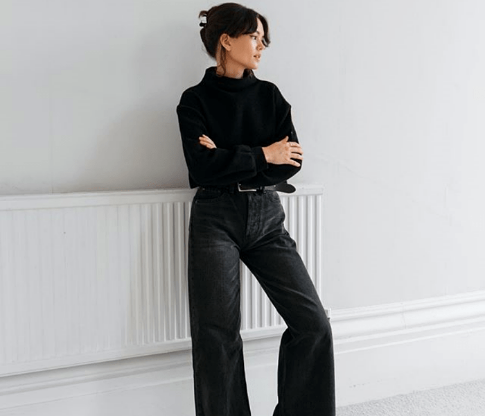 chica de cabello oscuro usando un suéter negro y jeans acampanados negros a la cintura