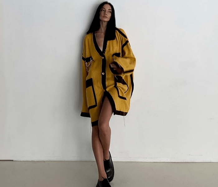 chica de cabello oscuro usando un cárdigan oversized amarillo con vistas negras y botines negros de suela gruesa