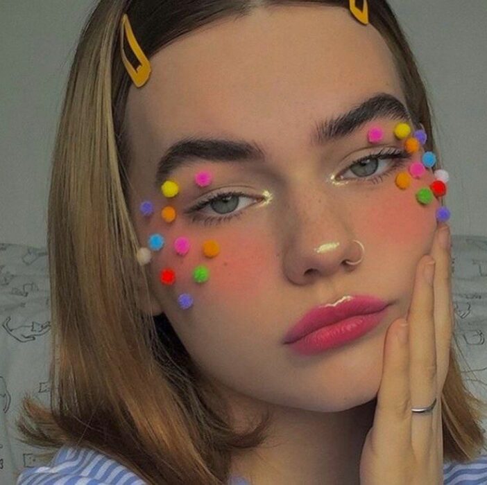 Chica con maquillaje en naranja y pequeños pompones
