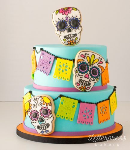 Pastel inspirado en el Día de muertos en color aguamarina de dos pisos con decoración de calaveras