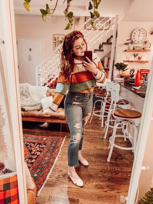Chica curvy usando balerinas, jeans rasgados y suéter rayado en colores otoñales