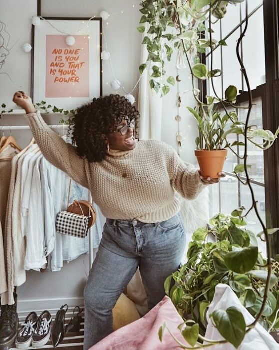 Chica curvy usando jeans deslavados y suéter tejido beige