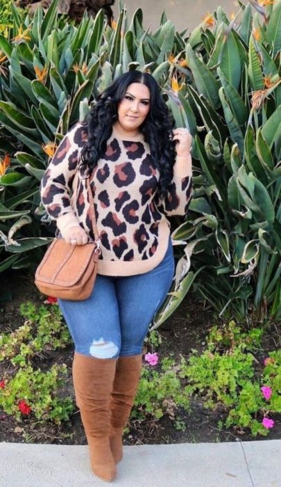 Chica curvy usando botas altas, bolsa camel, jeans de mezclilla y suéter de estampado animal print