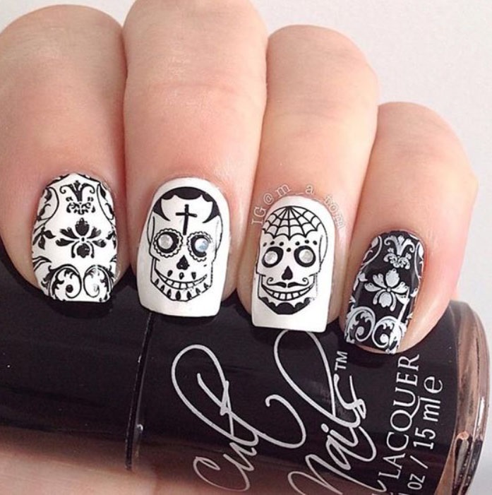 Uñas inspiradas en Día de Muertos con diseño de calaveras en color blanco y negro