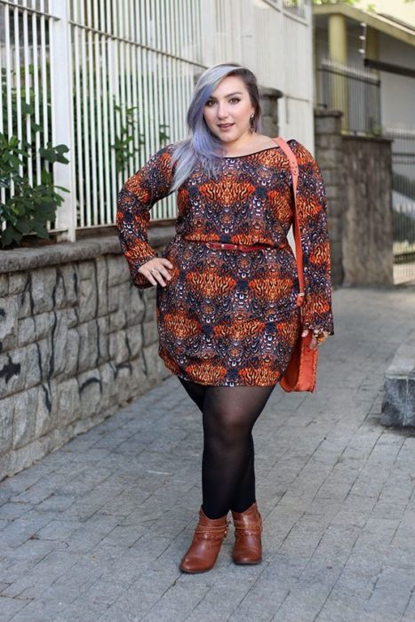 Chica usando vestido de manga larga corto de estampado bohemio, medias negras y botines camel