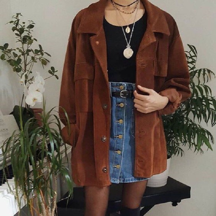 Chica usando medias negras, mini falda de mezclilla, top negro y camisa oversized color camel