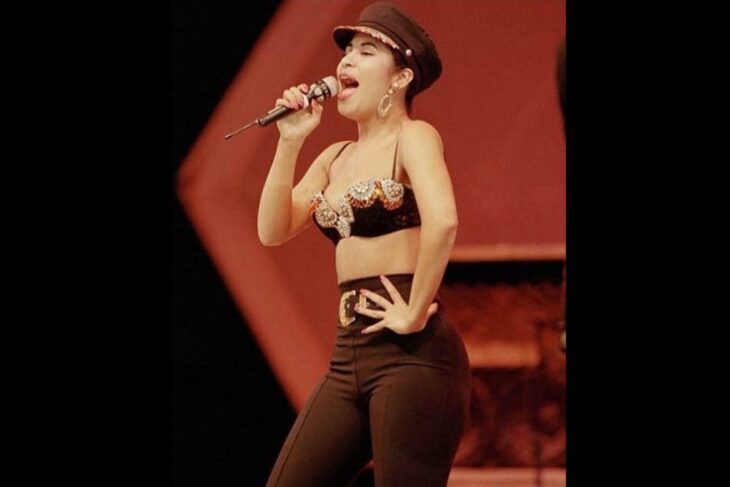 Selena Quintanilla usando leggins negros con un bustier de pedrería y boina negra 