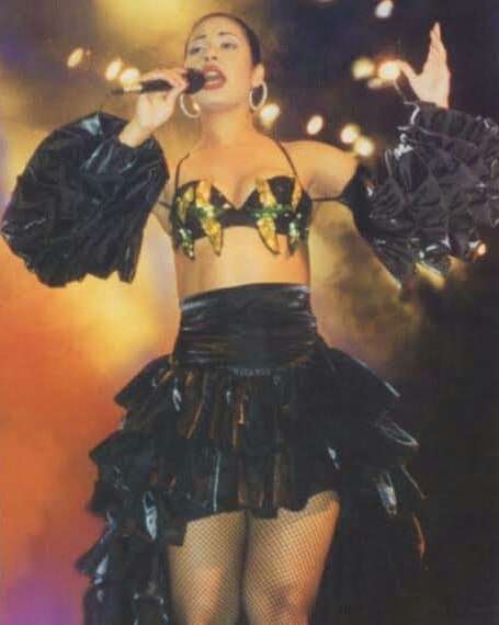 Selena Quintanilla durante un concierto usando una falda de volantes con crop top dorado 