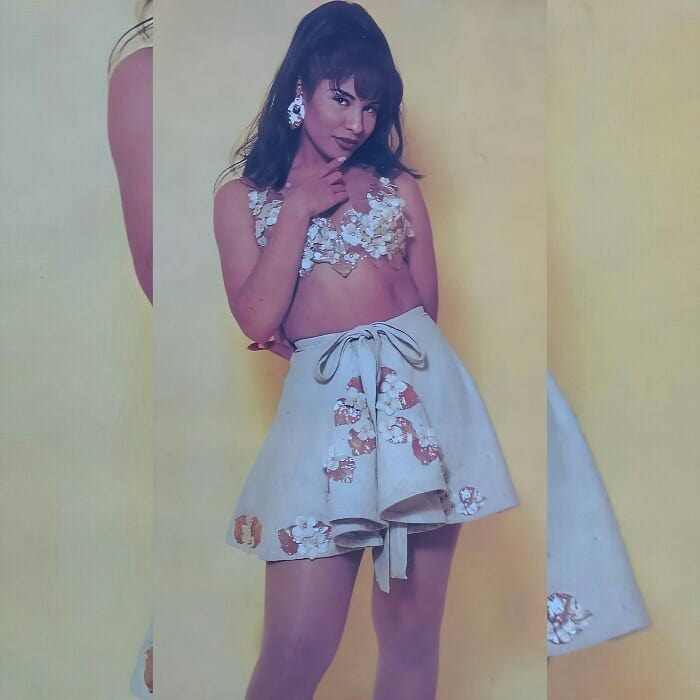 Selena Quintanilla usando un crop top beige y una falda a juego con detalles florales 