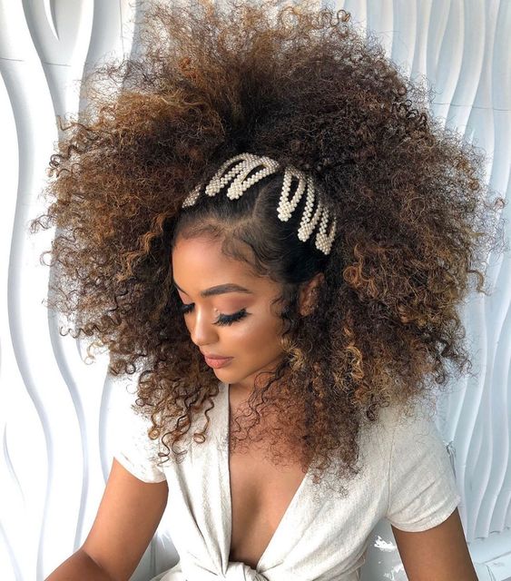 Chica con cabello rizado peinado con broches de perlas