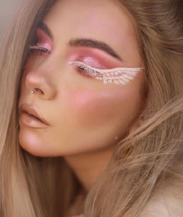 Maquillaje aesthetic en tonos rosados y blancos con alas de ángel en los ojos