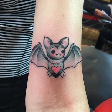 Tatuaje en forma de murciélago con corazón rosa