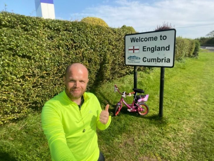 Hombre con chamarra verde tomando una selfie con una bicicleta