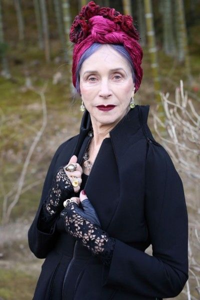 Mujer madura con cabello morado y banda roja con saco negro