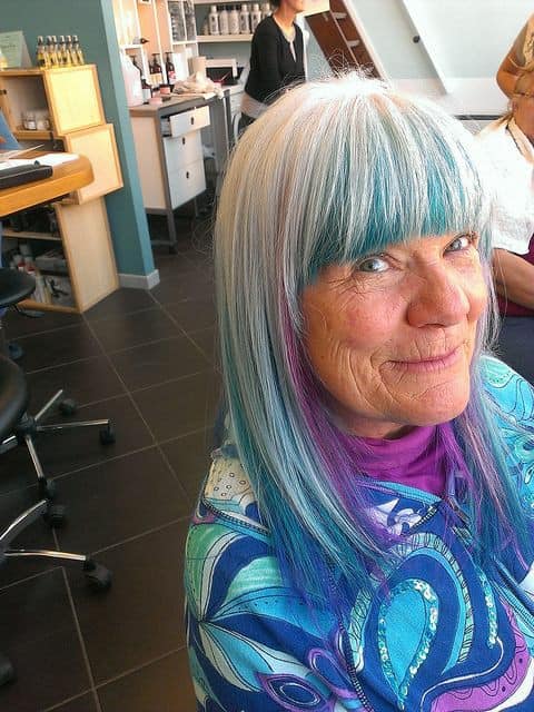 Mujer madura con melena mediana con canas y colores azul y morado