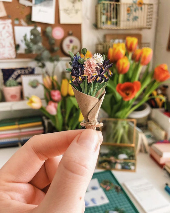 Miniramo de flores de papel de la artista Tania Lissova con flores en tonos morados envueltas en cartón marrón