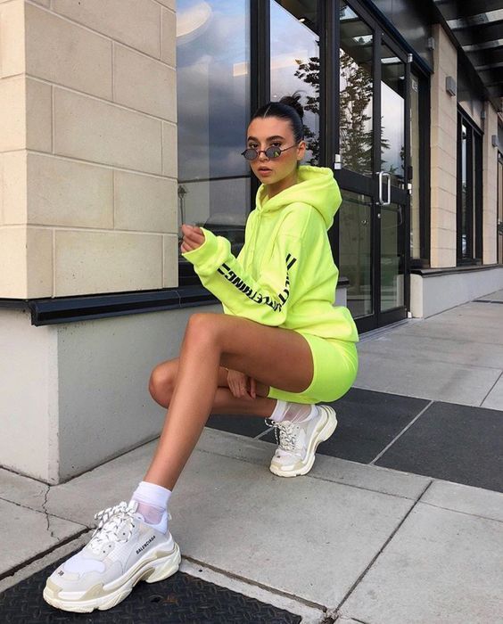 Chica posando agachada con outfit verde neón