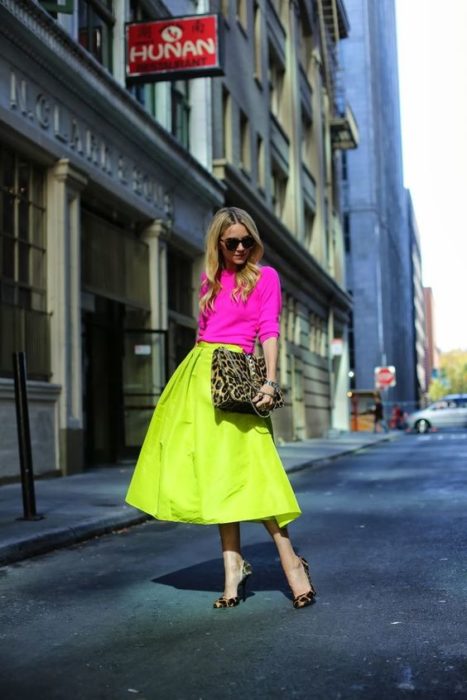 Chica rubia con blusa rosa neón y falda verde neón
