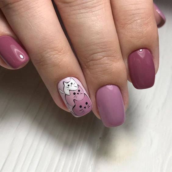 Manicura en colores morados con diseño de gatitos