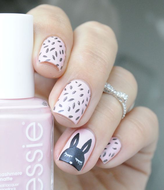 Manicura en rosa pastel con cintillas negras y un conejo negro