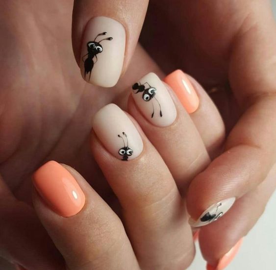 Manicura en tonos naranjas decorada con minihormigas en tonos negros