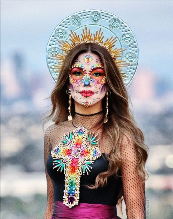 Maquillaje de catrina en colores vibrantes y cabello suelto y corona de aura de santos