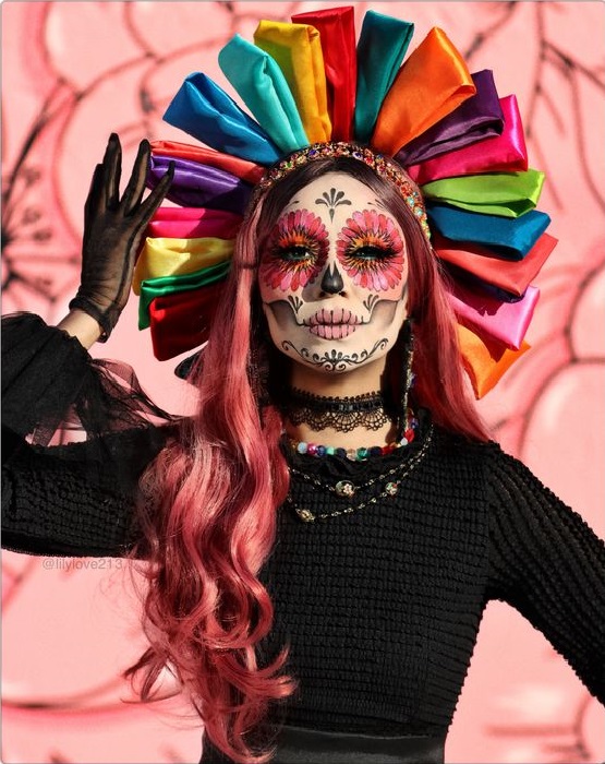 Maquillaje de catrina en rostro completo en colores rosas, negros y blancos, con corona de listones como muñeca tradicional mexicana