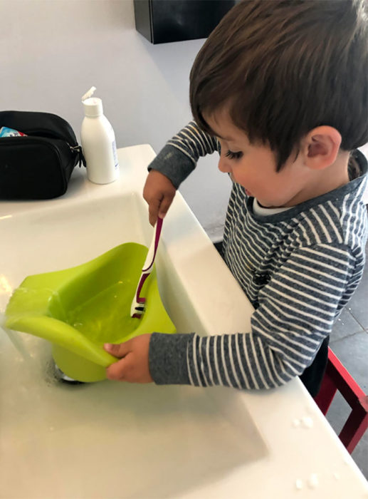 Niño lavando el orinal con un cepillo de dientes