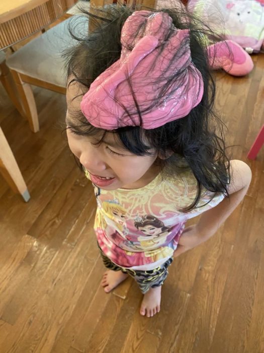 Niña con el cabello lleno de slime de color rosa