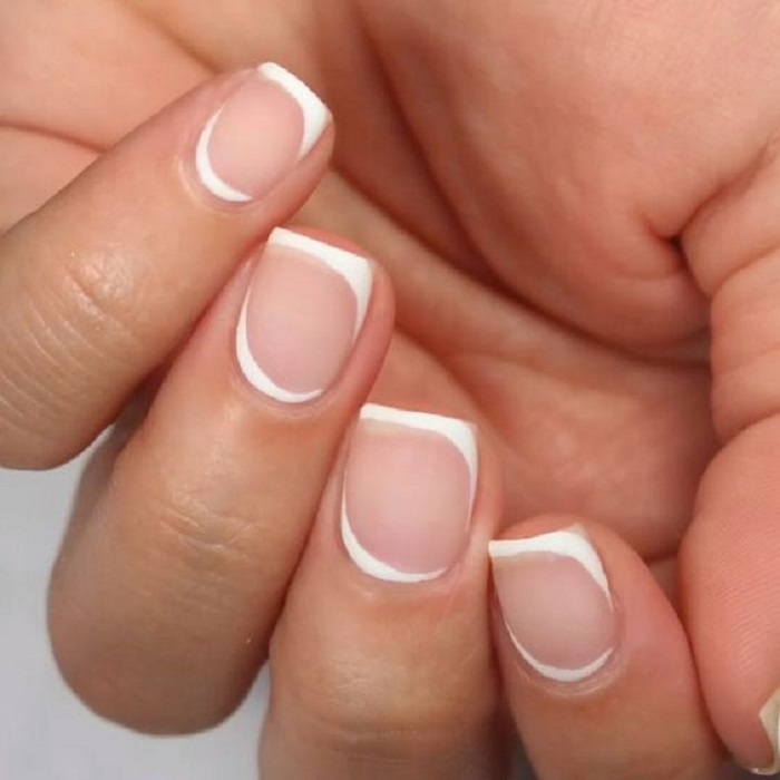 Diseño de manicura en uñas cortas en color transparente con detalles en blanco