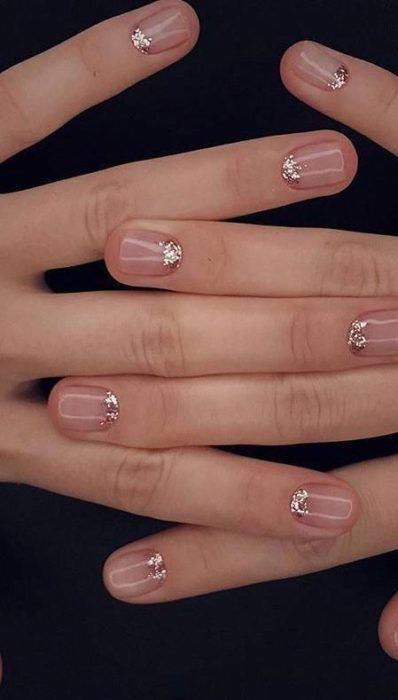 Diseño de manicura en uñas cortas transparentes con la zona de la luna dorada