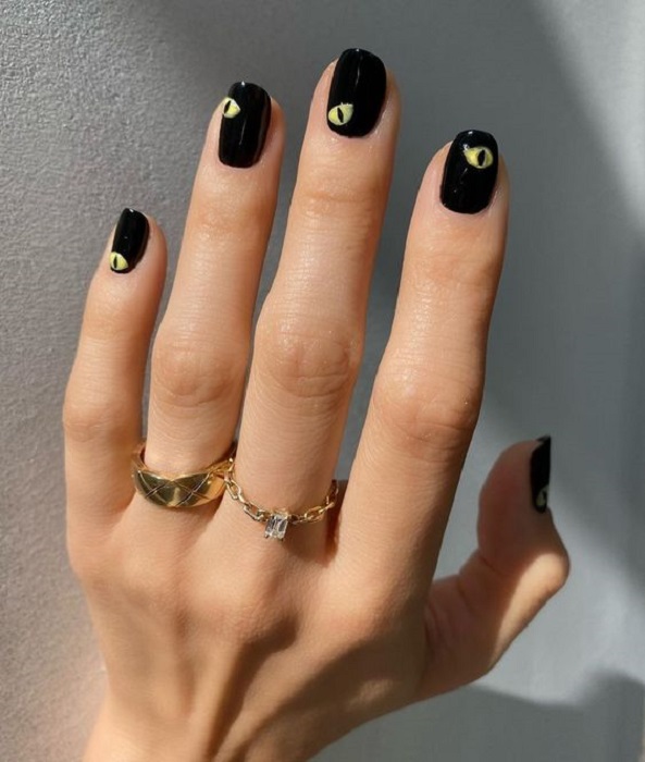 Diseño de manicura en uñas cortas en color negro con ojos pintados