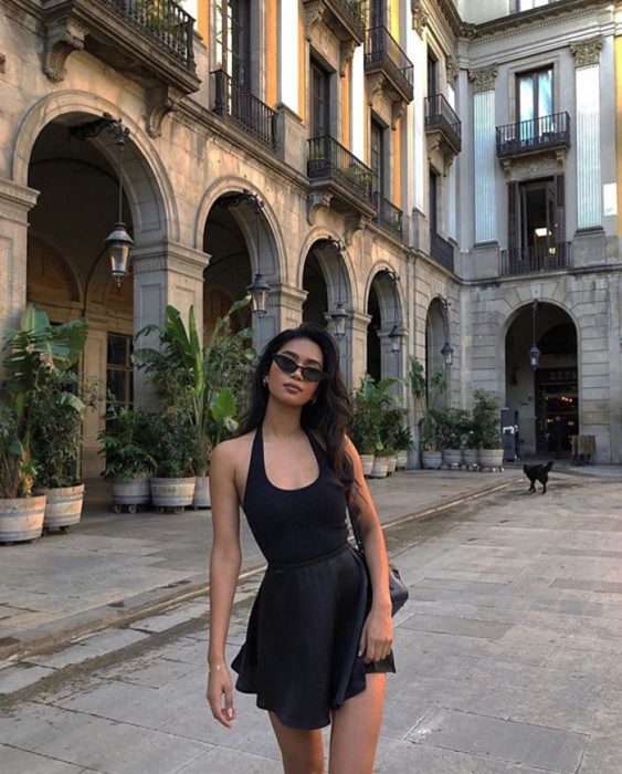 Chica usando falda negra y top negro, de cabello oscuro con lentes de sol