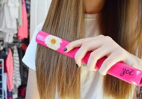 Chica de cabello rubio planchando su cabello