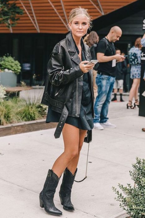 Chica posando con botas vaqueras y un outfit negro
