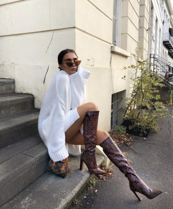 Chica posando sentada con botas largas de color guinda