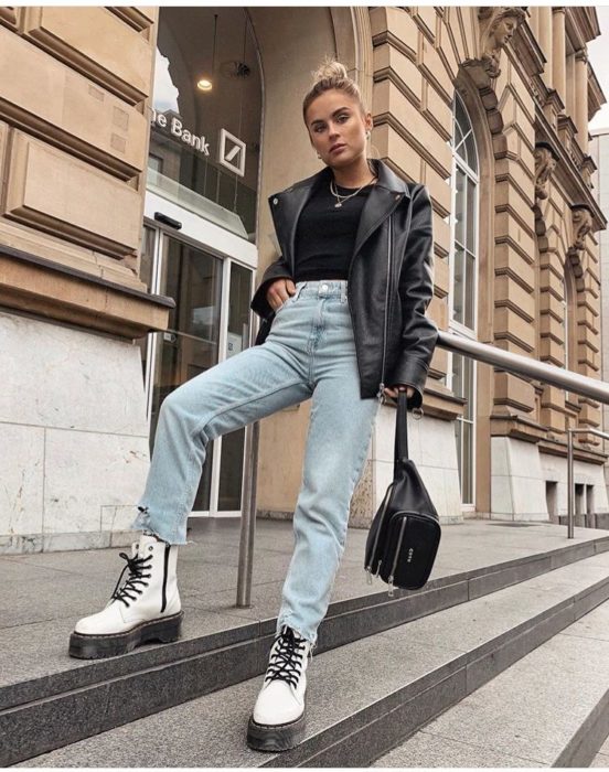 Chica con botas Dr. Martens blancas, jeans y chaqueta negra