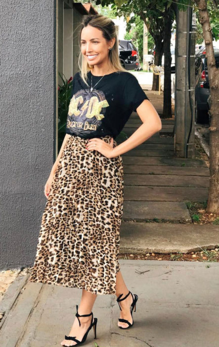 Chica usando una falda midi con estampado animal print con una blusa negra con el logo de AC/DC