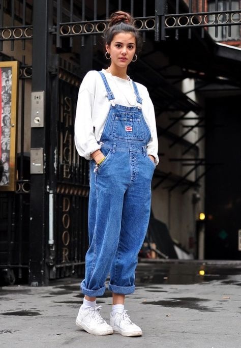 Chica con chongo alto, overol de mezclilla y blusa y tenis blancos
