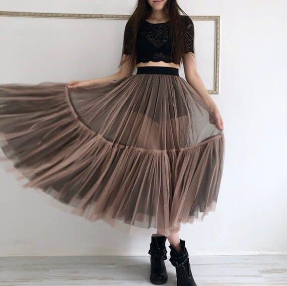 Chica llevando falda en tono rosa oscuro con transparencia y botas negras