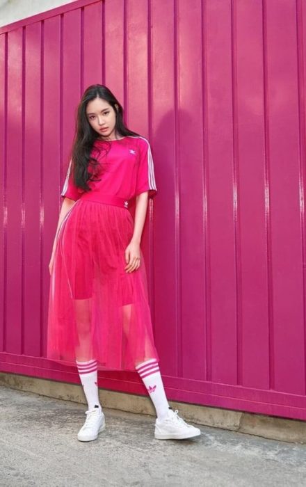 Chica llevando camisa deportiva con falda a transparencias en tono rosa fucsia