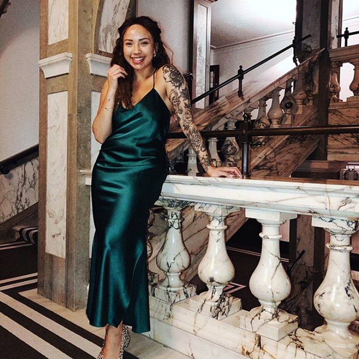 chica morena con cabello largo usando un vestido de satén color esmeralda